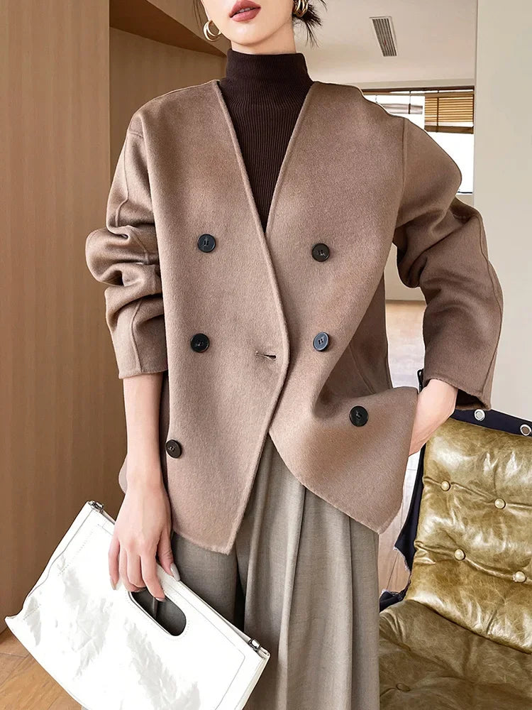 Person wearing a brown coat with black buttons indoors.