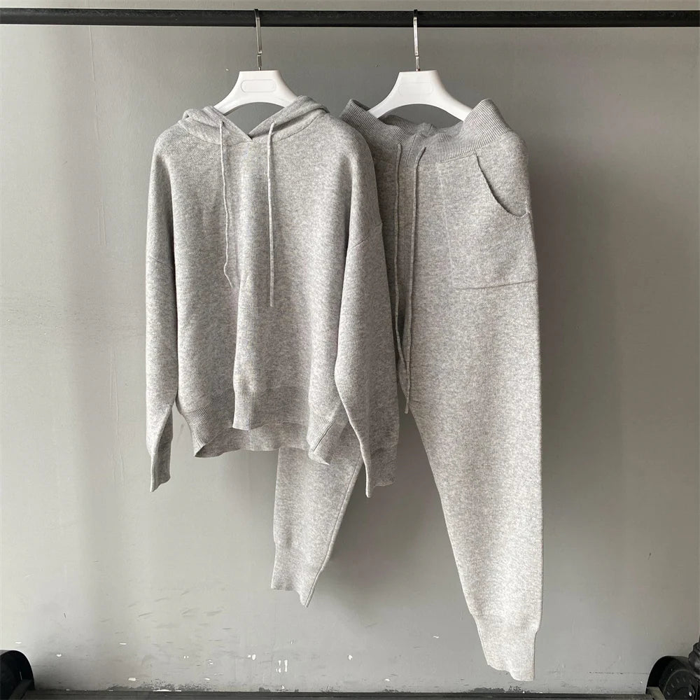 Gray hoodie and jogger pants on hangers against a plain wall.