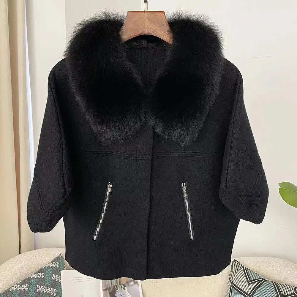 Black coat with fur collar on a hanger against a neutral background