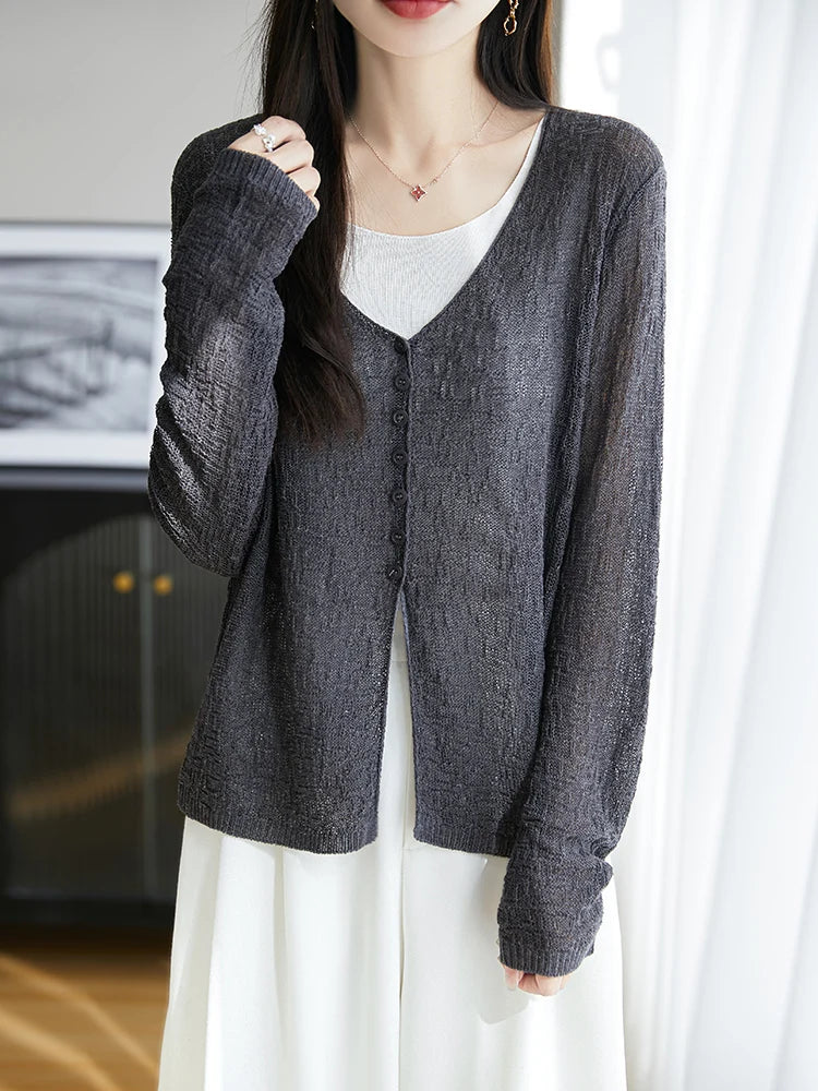 Person wearing a gray cardigan over a white shirt in a neutral setting