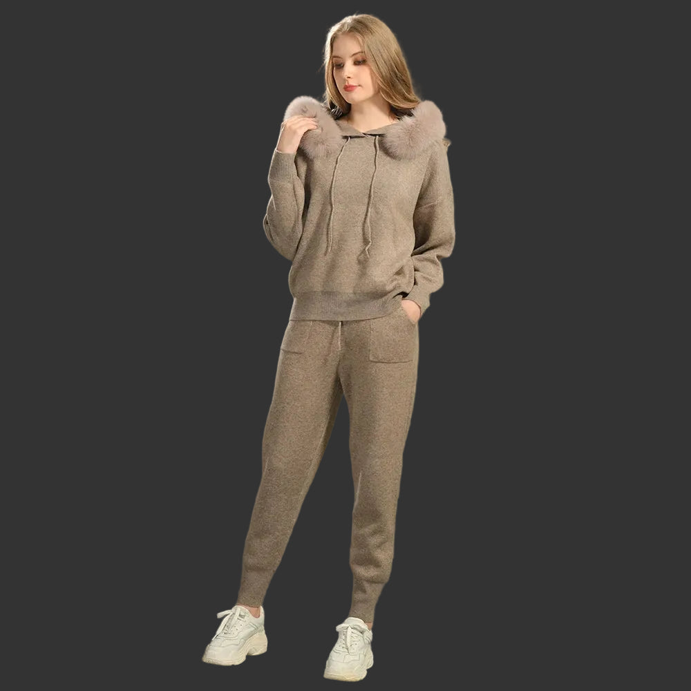 Woman wearing a brown tracksuit with fur-lined hood against a gray background