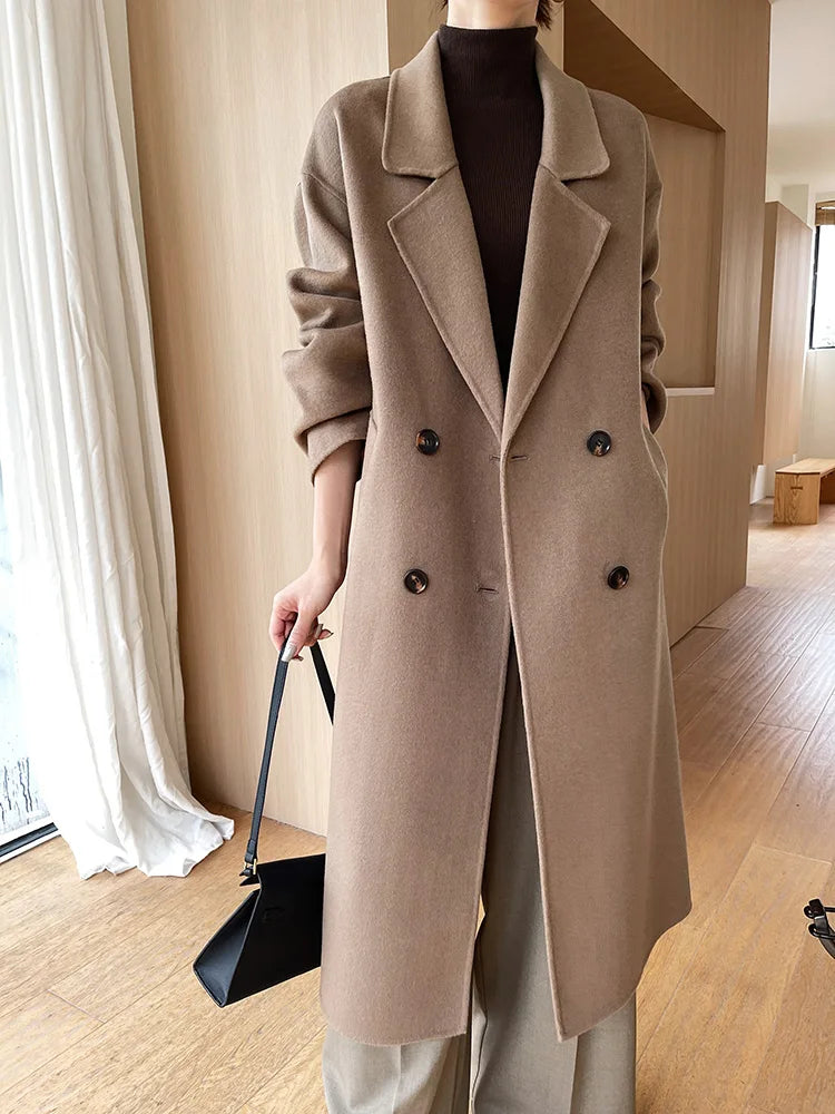 Person wearing a long beige coat in an indoor setting