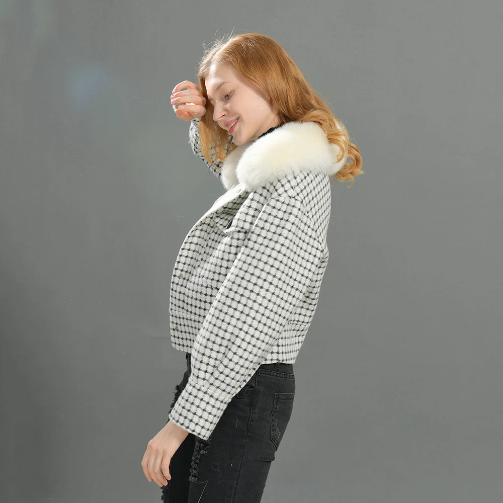 Woman wearing a checkered jacket with a fur-lined hood against a gray background