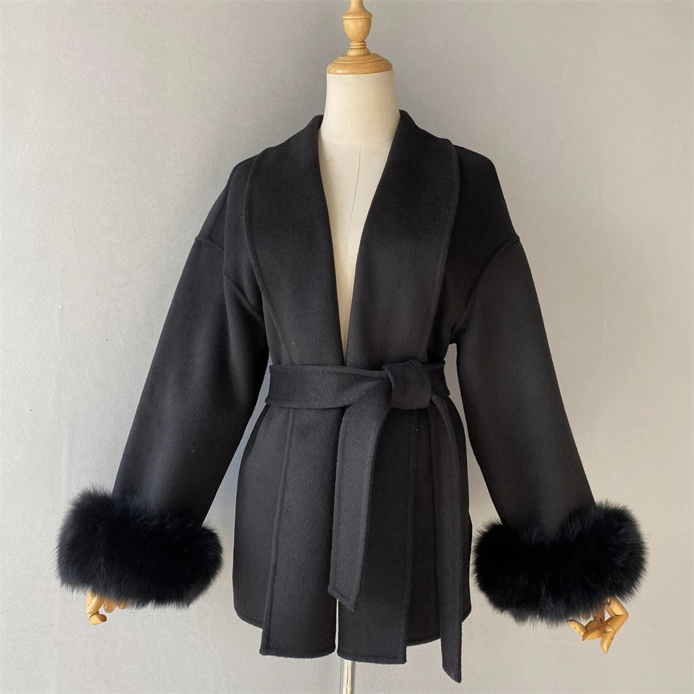 Black coat with fur cuffs on a mannequin against a plain background