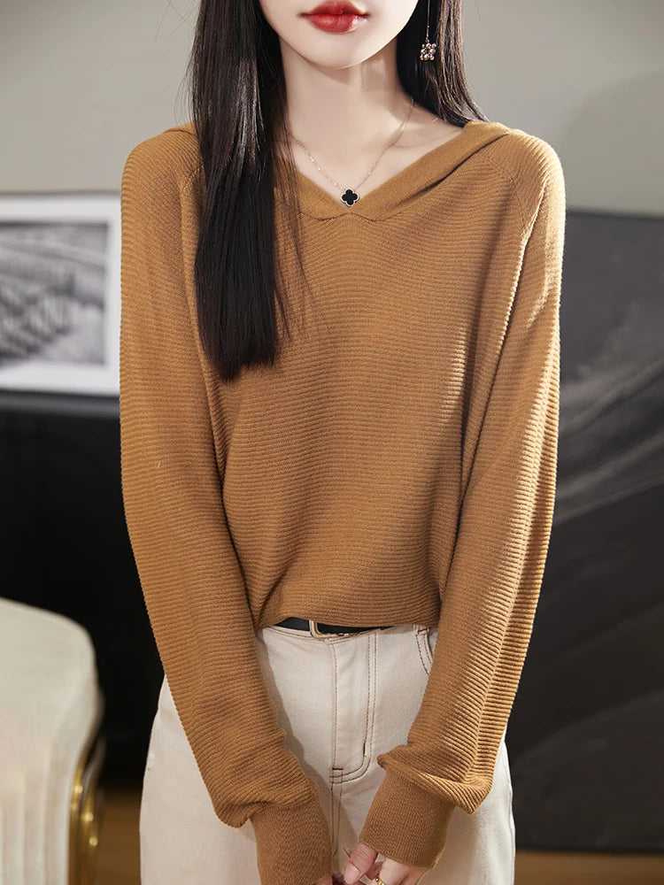 Person wearing a brown sweater and white pants indoors