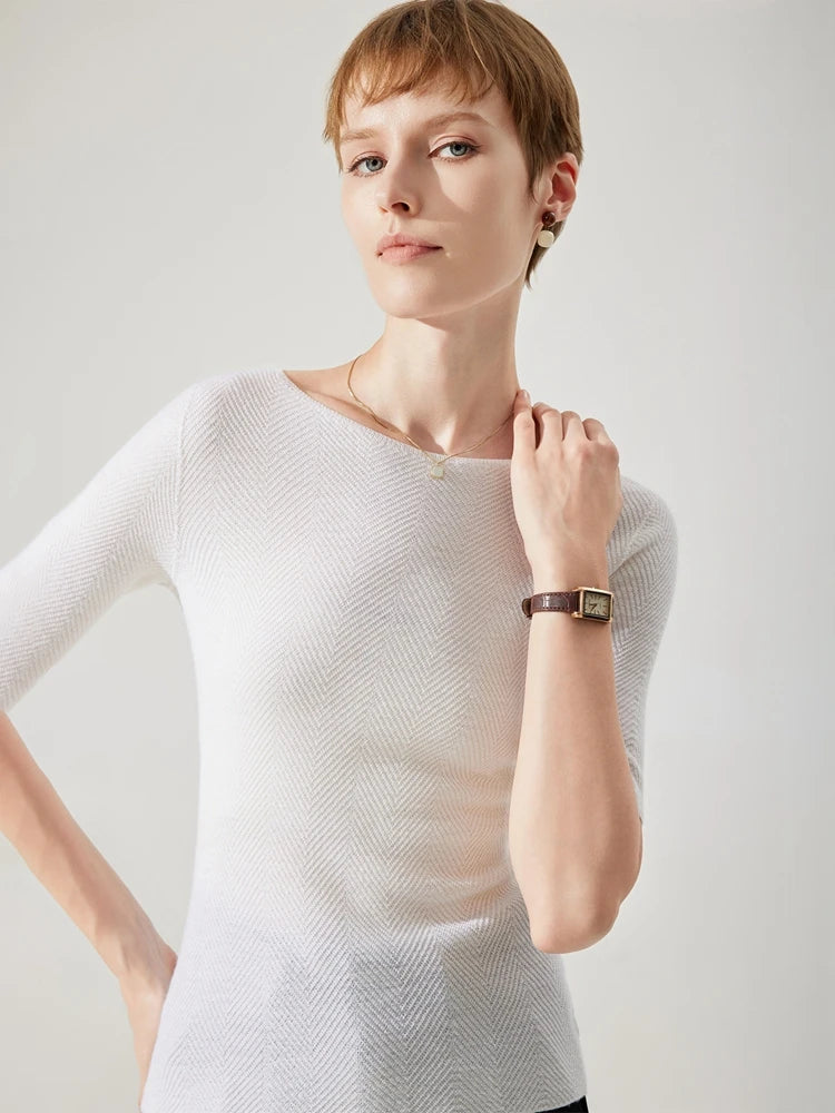 Woman wearing a white textured sweater against a plain background
