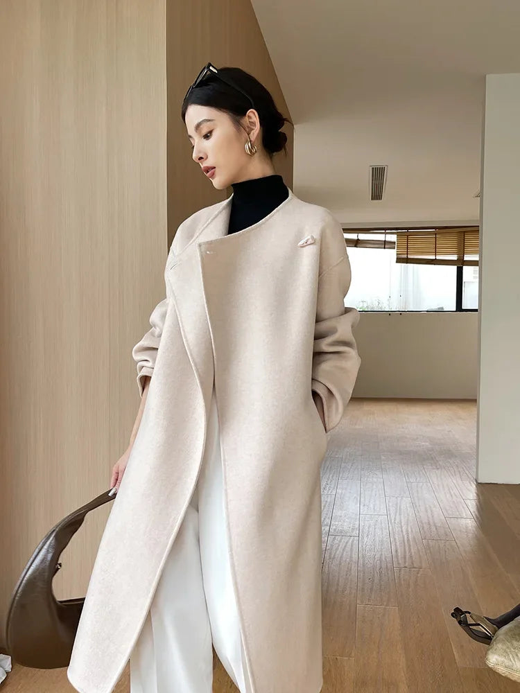 Woman wearing a long beige coat in an indoor setting