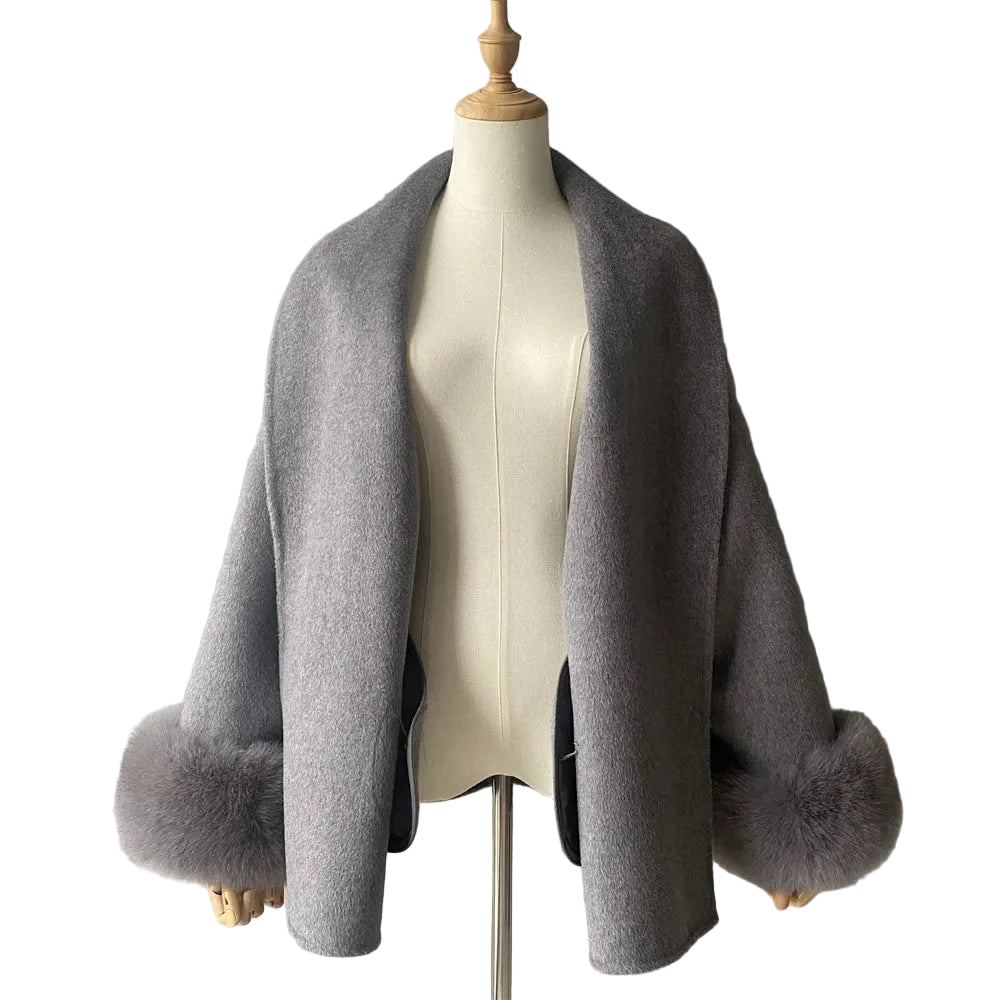 Gray shawl with fur trim on a mannequin against a plain background