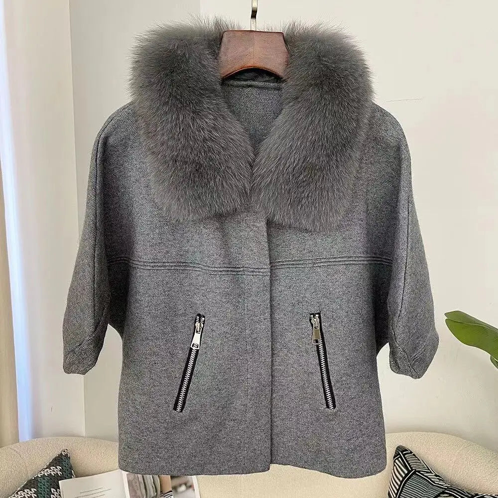 Gray coat with fur collar on a hanger against a neutral background