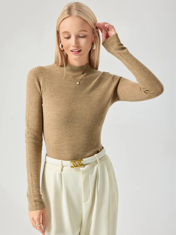 Woman wearing a beige long-sleeve top and white pants on a light gray background