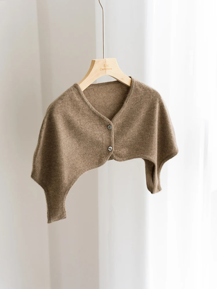 Brown knitted shrug on a wooden hanger against a white background