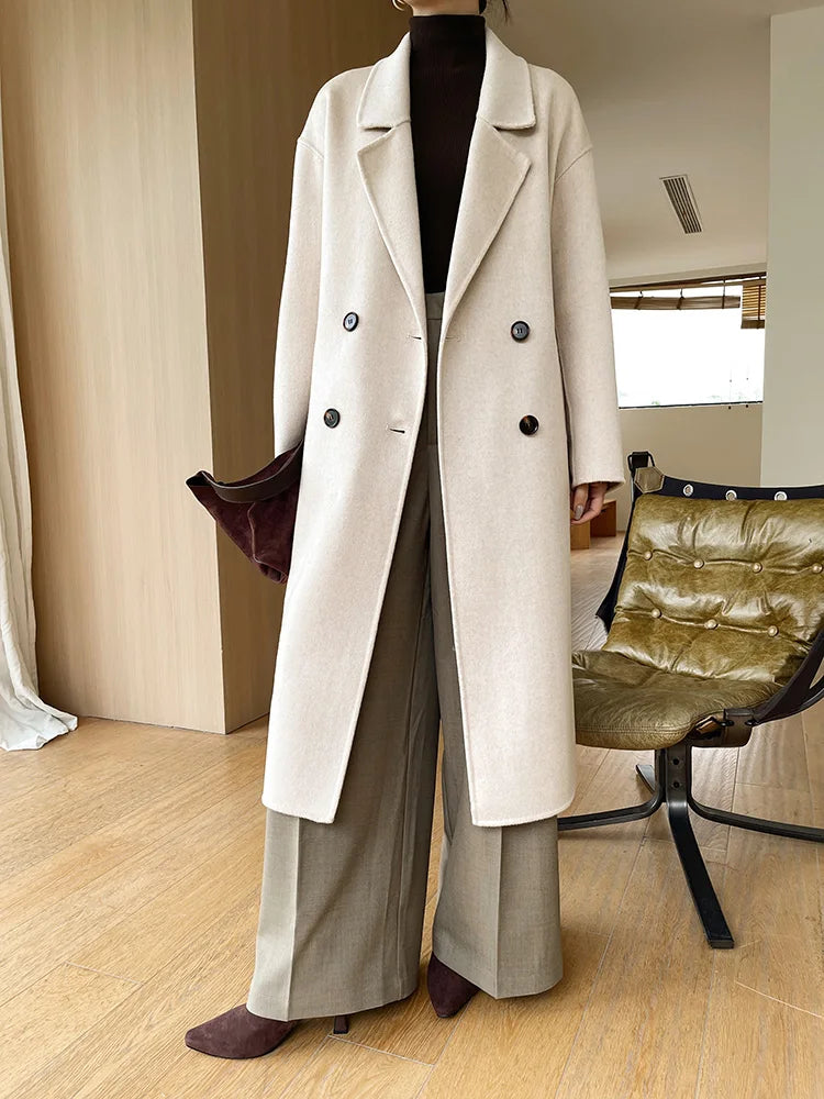 Person wearing a long beige coat in an indoor setting