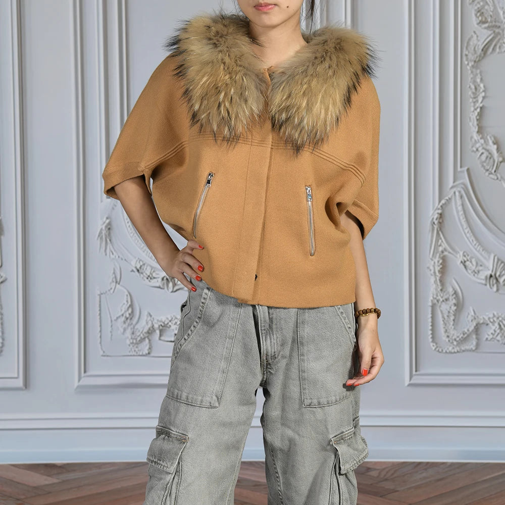 Person wearing a brown jacket with a fur collar and gray cargo pants against a decorative wall.