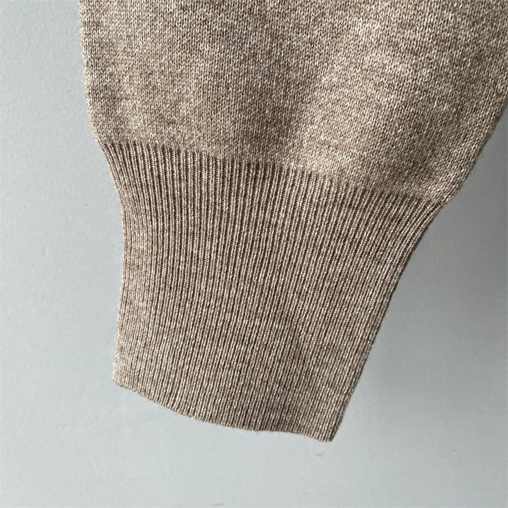Close-up of a brown knitted sweater sleeve on a light gray background