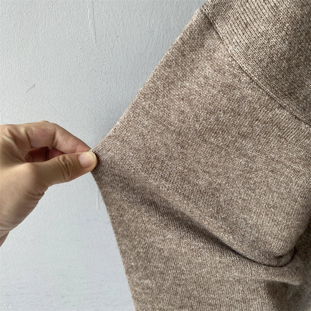 Close-up of a hand holding a beige fabric against a light gray background