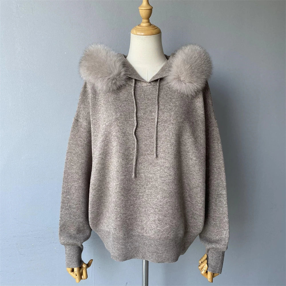 Gray hoodie with fur pom-poms on a mannequin against a plain background
