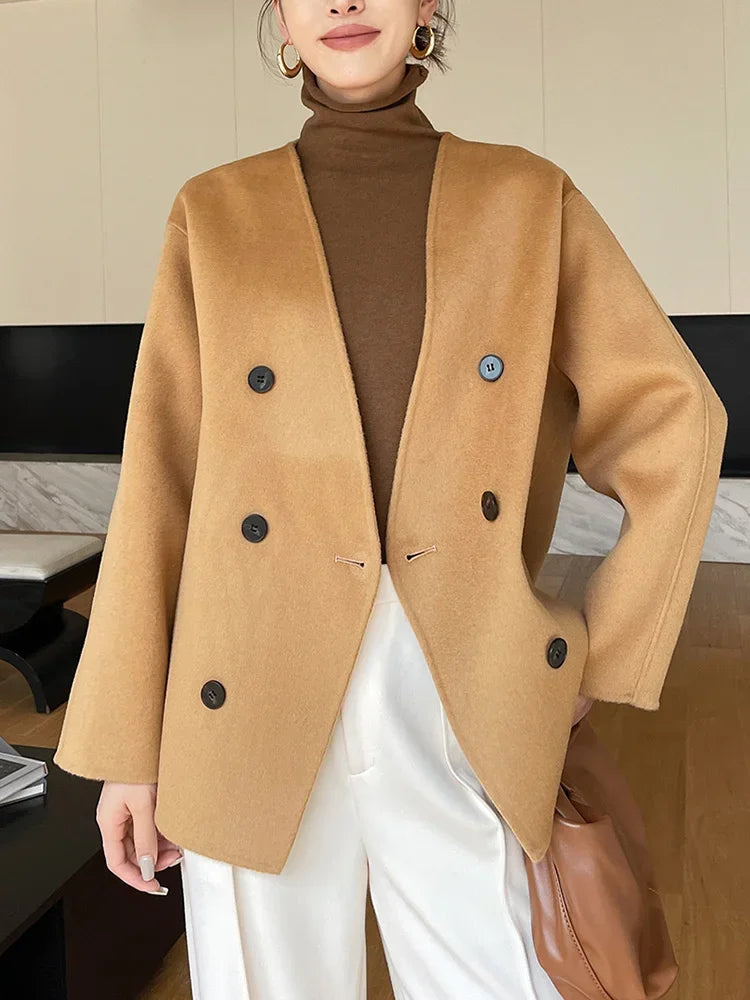 Person wearing a tan coat with black buttons indoors.