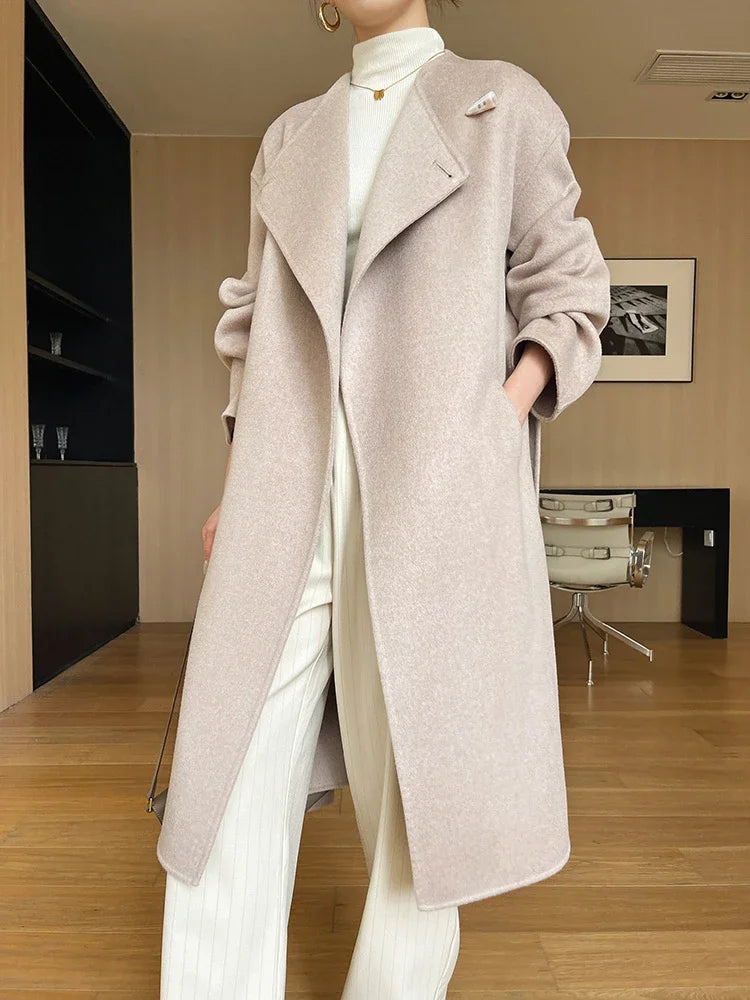 Person wearing a long beige coat in an indoor setting