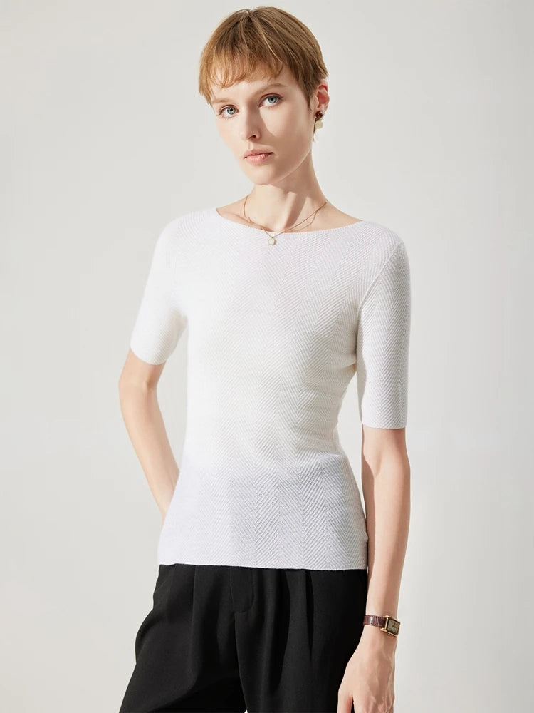 Woman wearing a white textured top and black pants on a light gray background