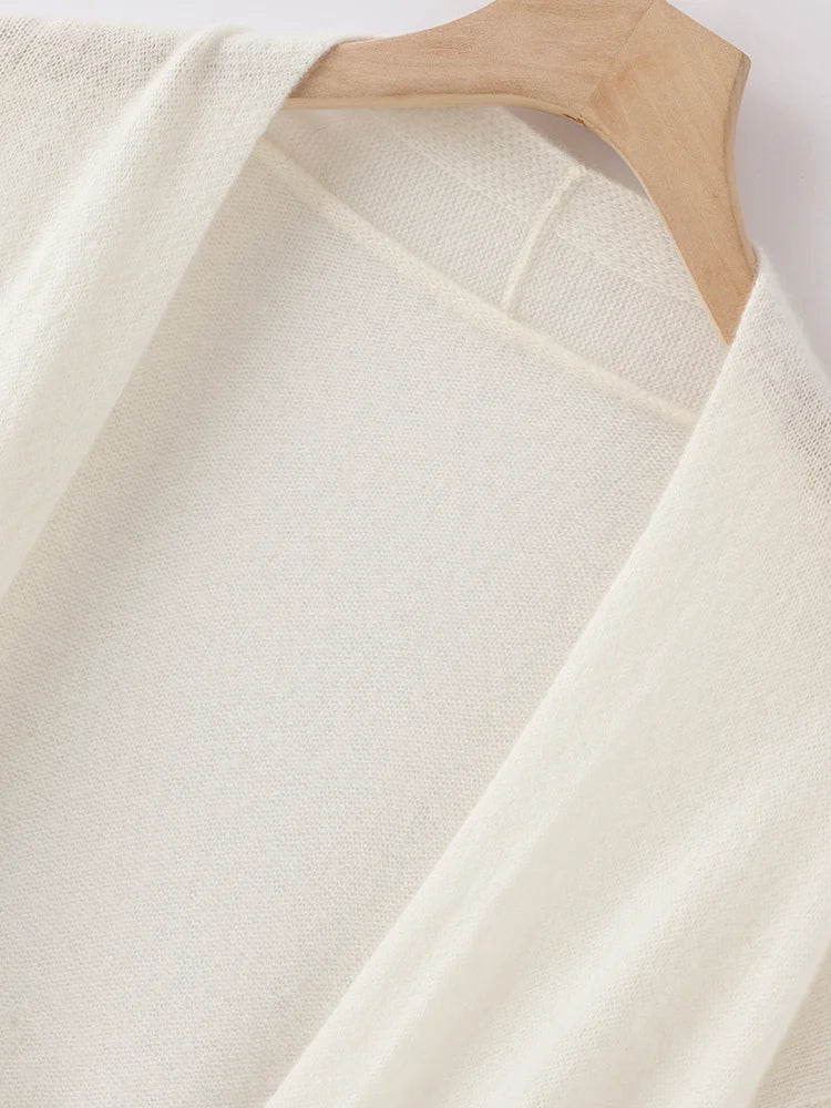 White sweater on a wooden hanger against a white background