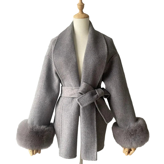 Gray coat with fur cuffs and belt on a mannequin against a plain background