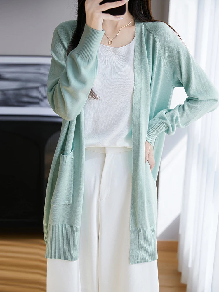 Person wearing a light green cardigan over a white outfit, standing indoors.