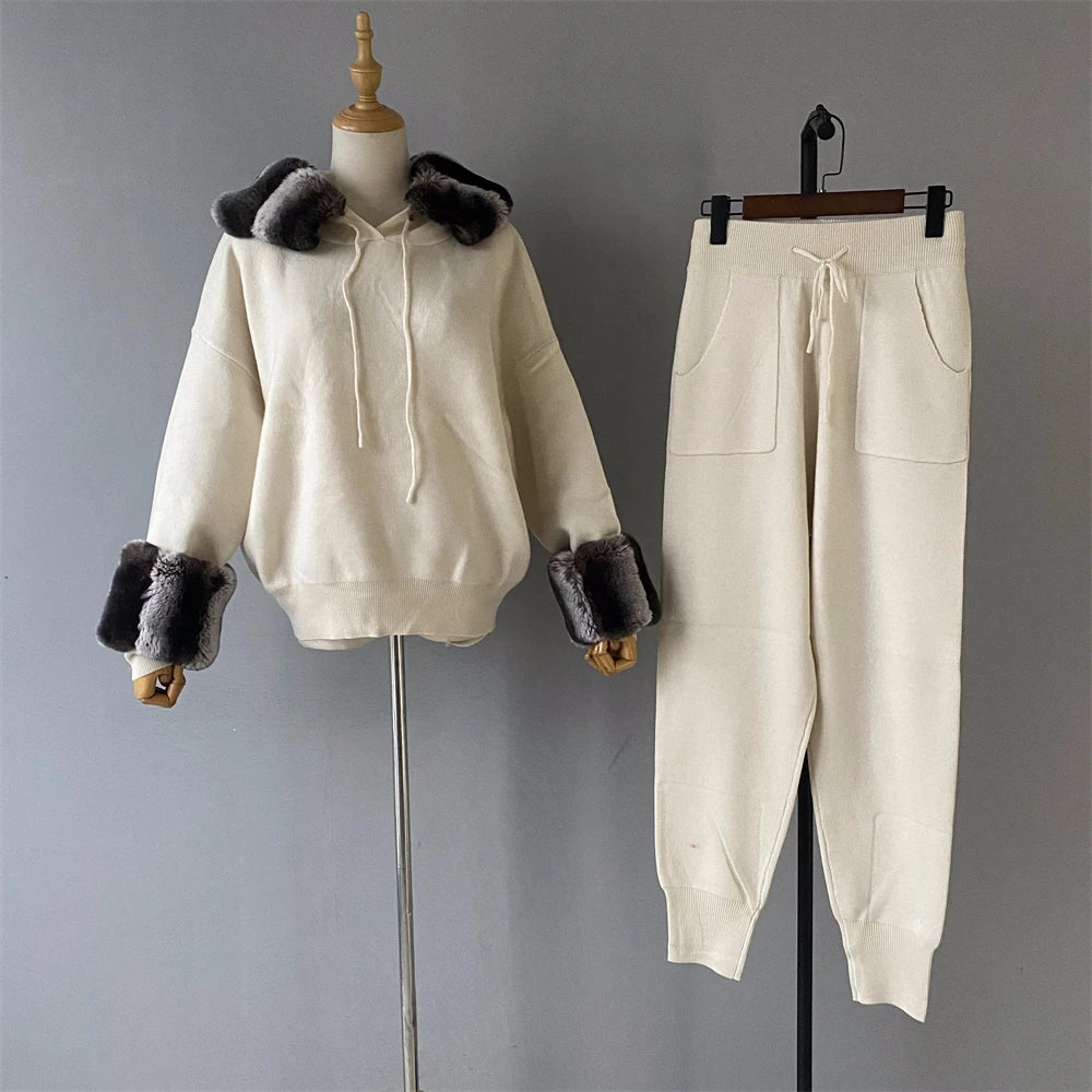 White hoodie with fur trim and matching pants on a gray background