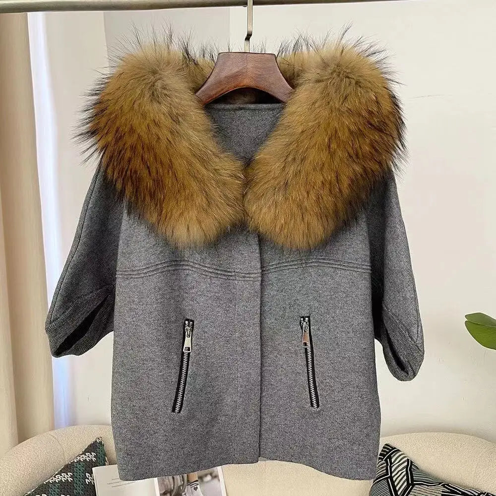 Gray coat with a fur-lined hood on a hanger against a neutral background