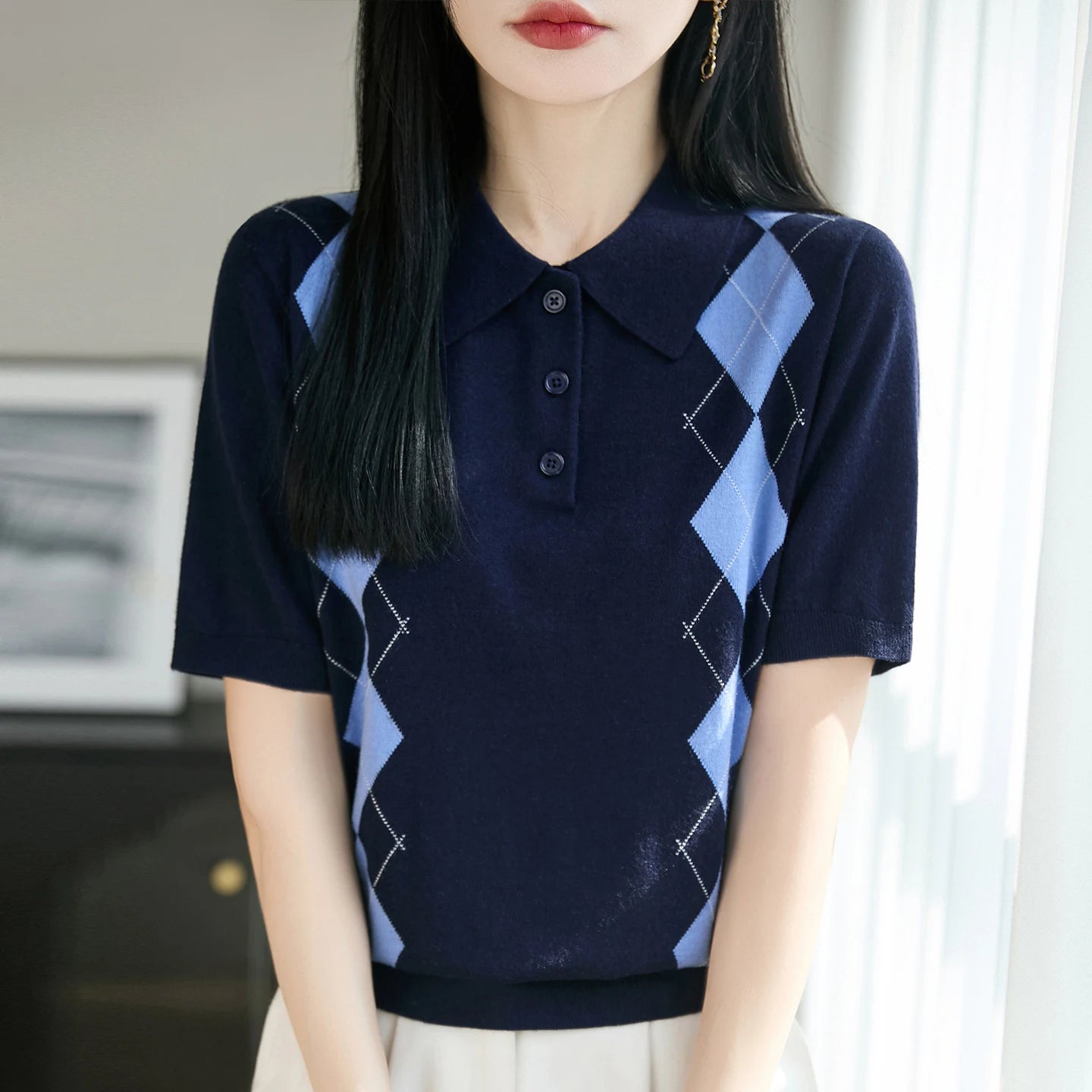 Person wearing a navy blue and light blue argyle patterned shirt indoors.