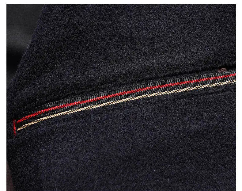 Close-up of a dark fabric with red and white stitching, likely from a jacket or coat.