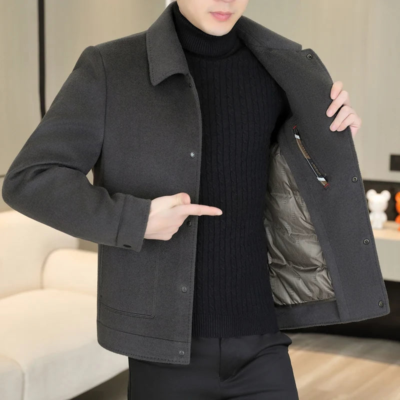 Person wearing a dark gray coat with a black interior, pointing to the pocket.