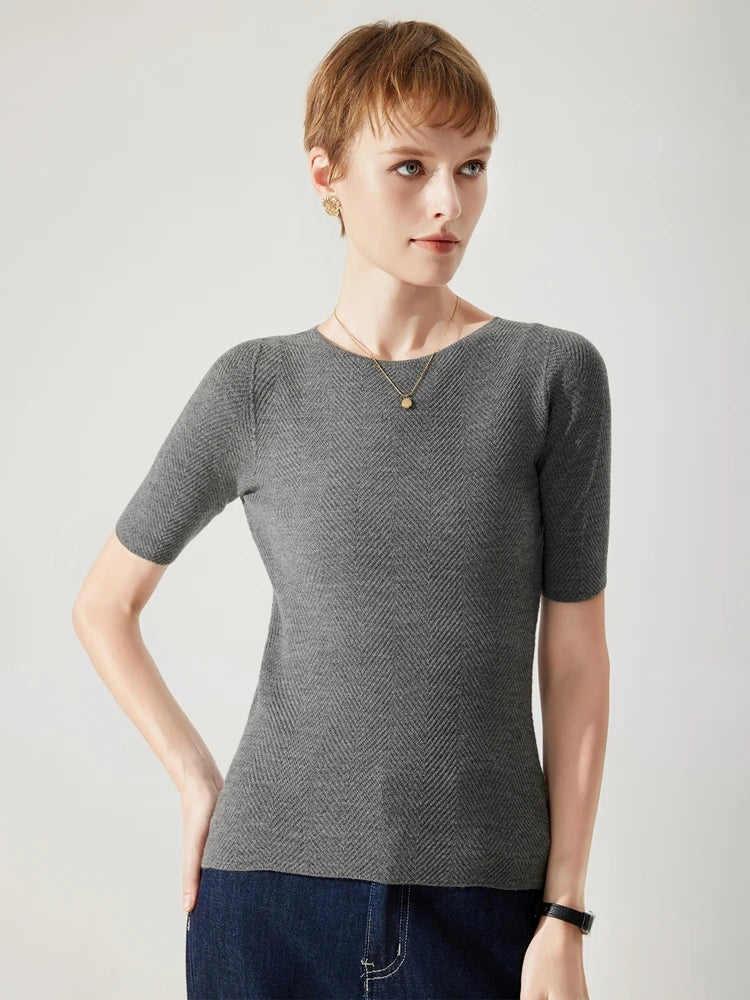 Woman wearing a gray short-sleeve knit top against a plain background
