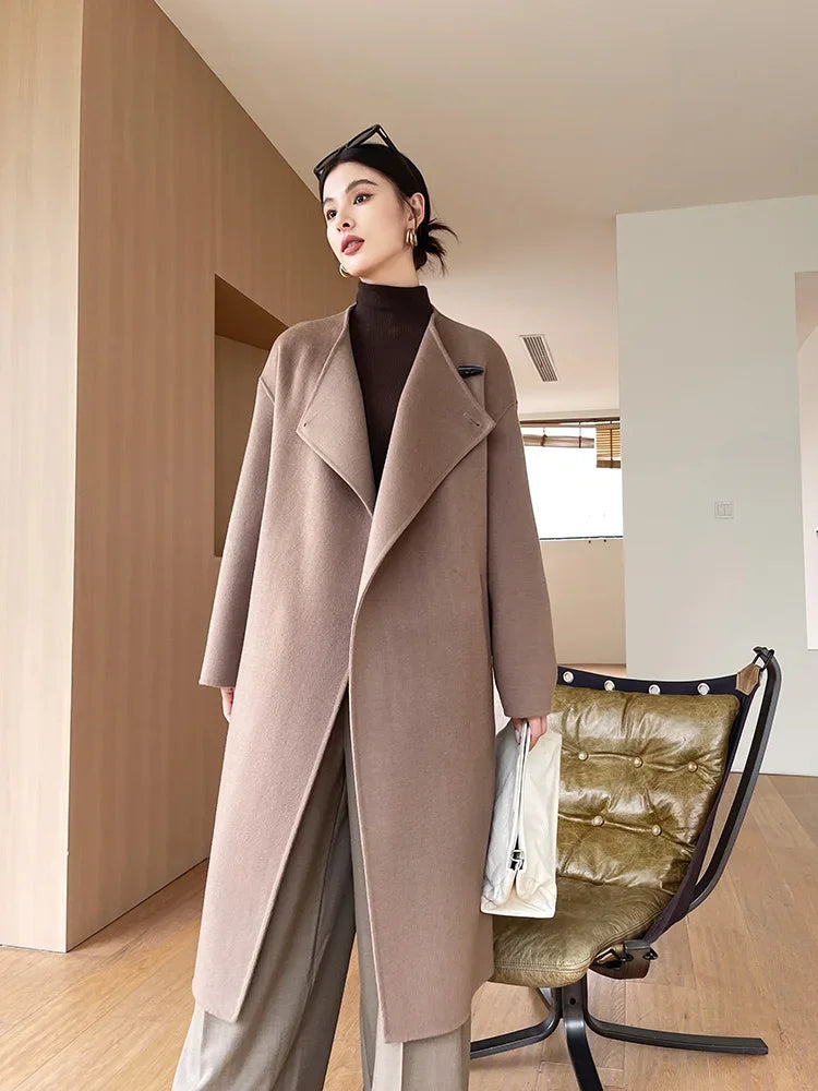Woman wearing a long beige coat in an indoor setting