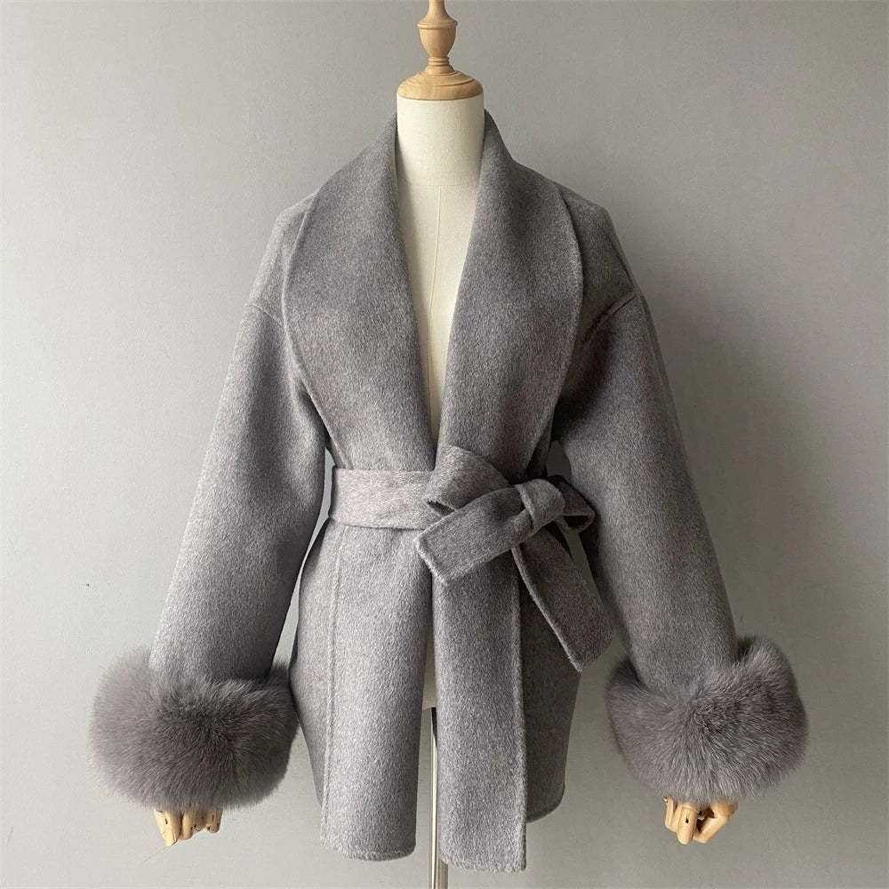 Gray coat with fur cuffs on a mannequin against a plain background