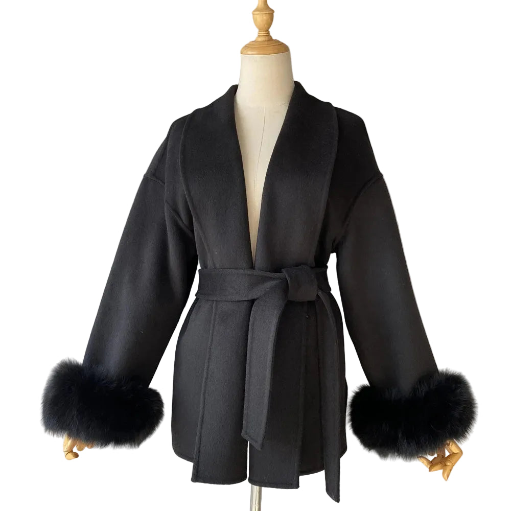 Black coat with fur cuffs on a mannequin against a plain background