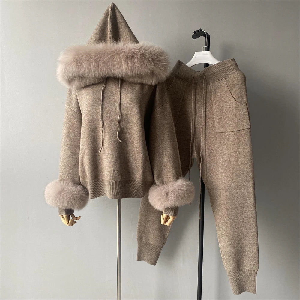 Beige hoodie and pants set with fur trim on a hanger against a gray background