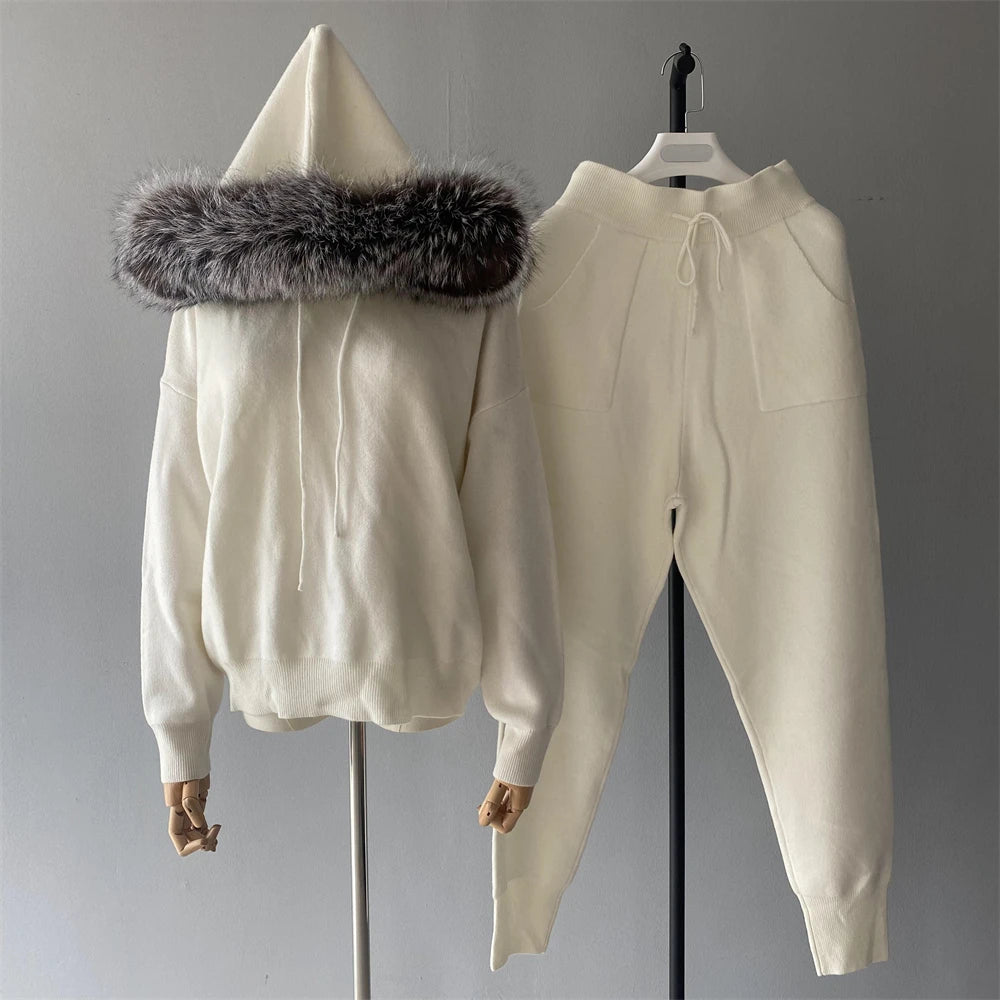 White hoodie with fur trim and matching pants on a gray background