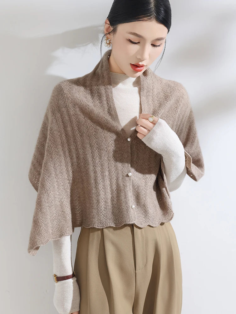 Woman wearing a beige knitted shawl over a white blouse with a plain background