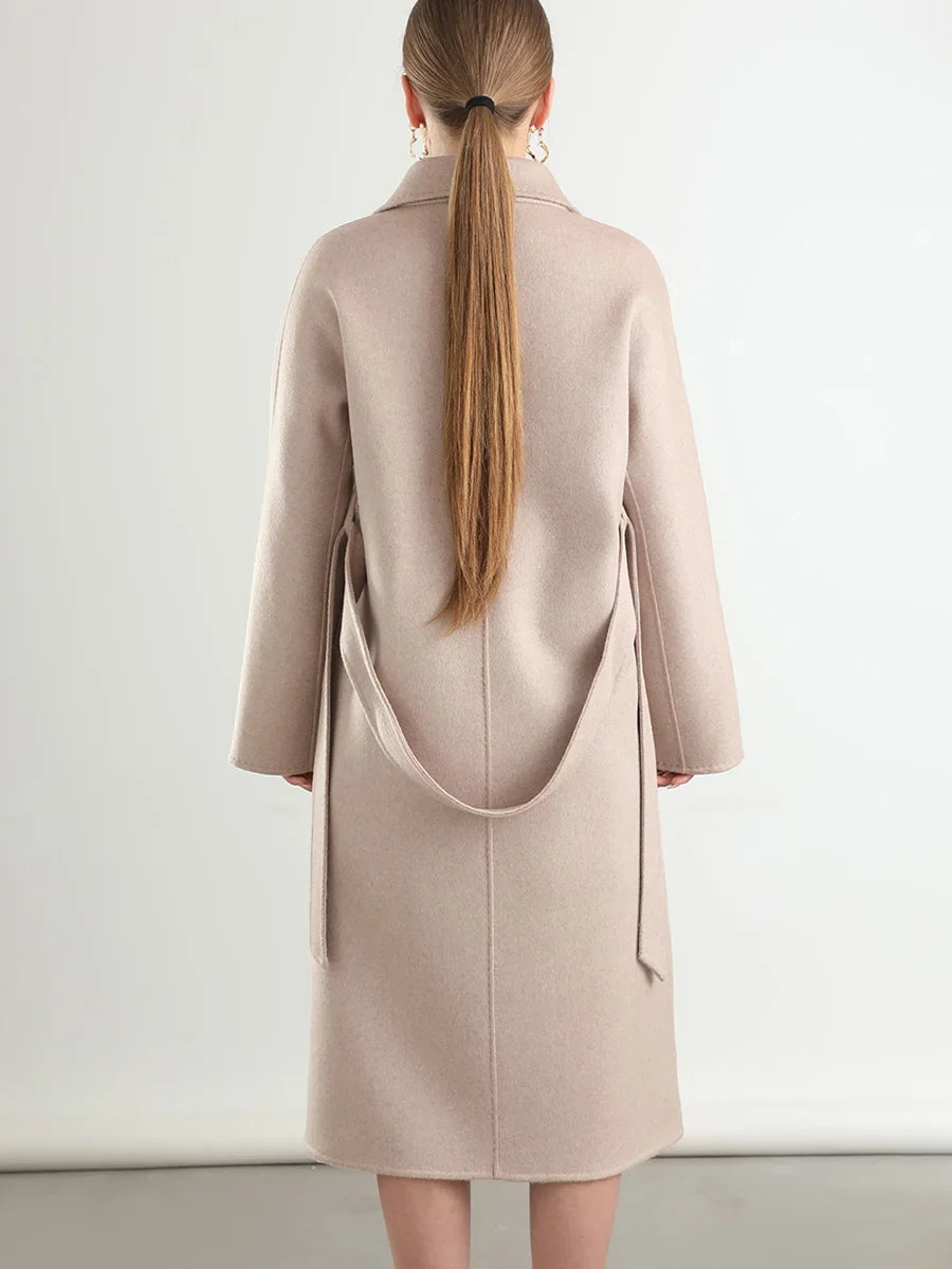 Person wearing a beige coat with a plain background