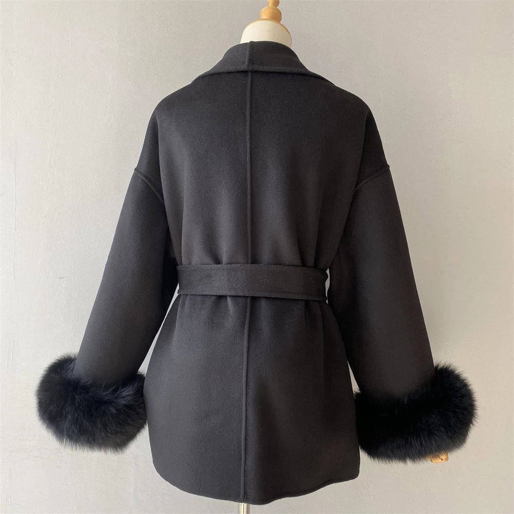 Dark gray coat with fur cuffs on a mannequin against a plain background