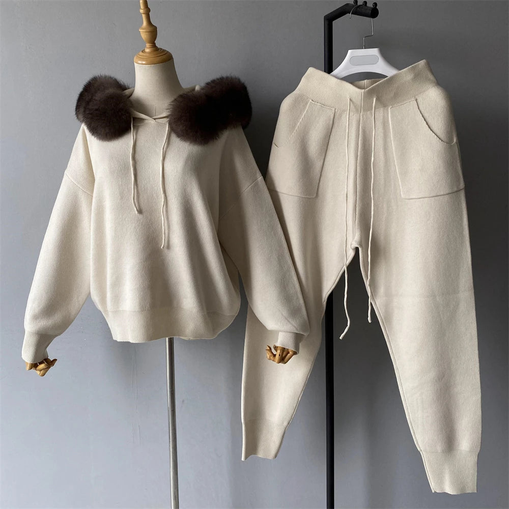 Beige hoodie with fur-lined hood and matching pants on a mannequin and hanger against a gray background.