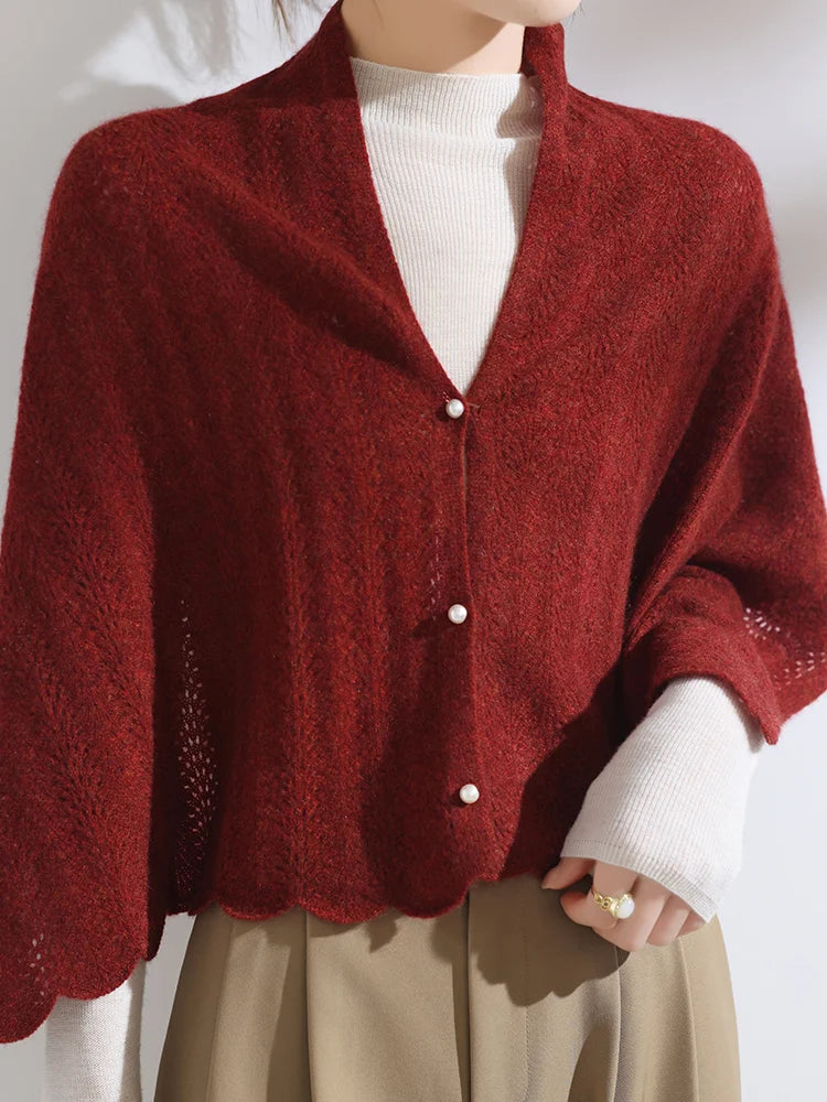 Red knitted cardigan over a white sweater and beige pants on a plain background