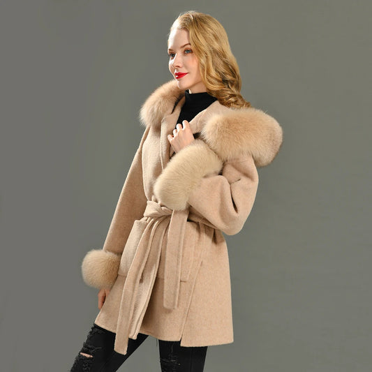 Woman wearing a beige coat with fur trim on a gray background
