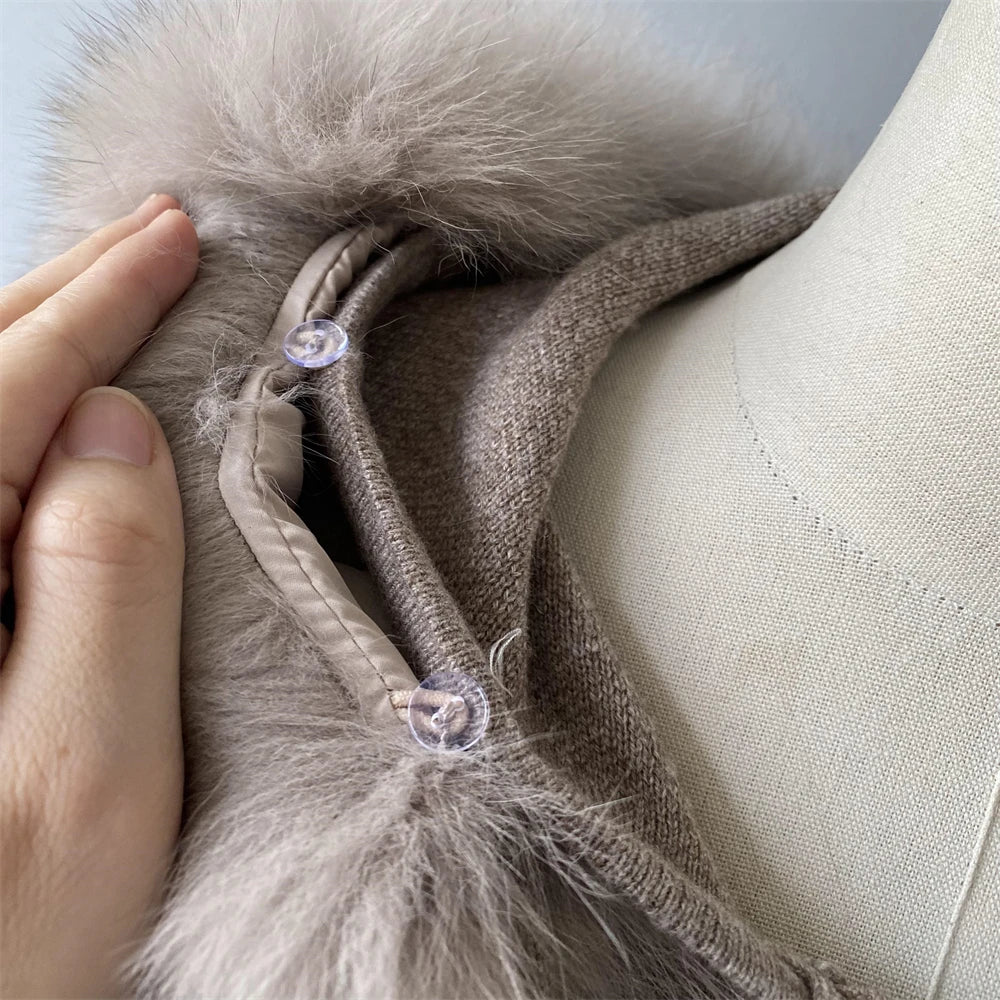 Close-up of a beige fabric with fur trim and decorative buttons, held by a hand.