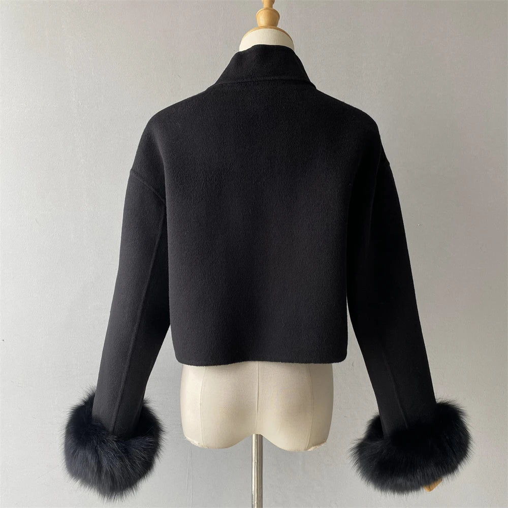 Black jacket with fur cuffs on a mannequin against a plain background