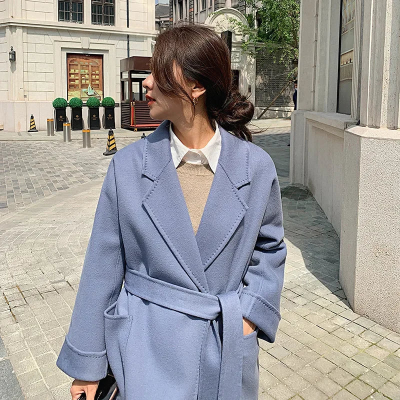 Woman wearing a blue coat walking on a city street.