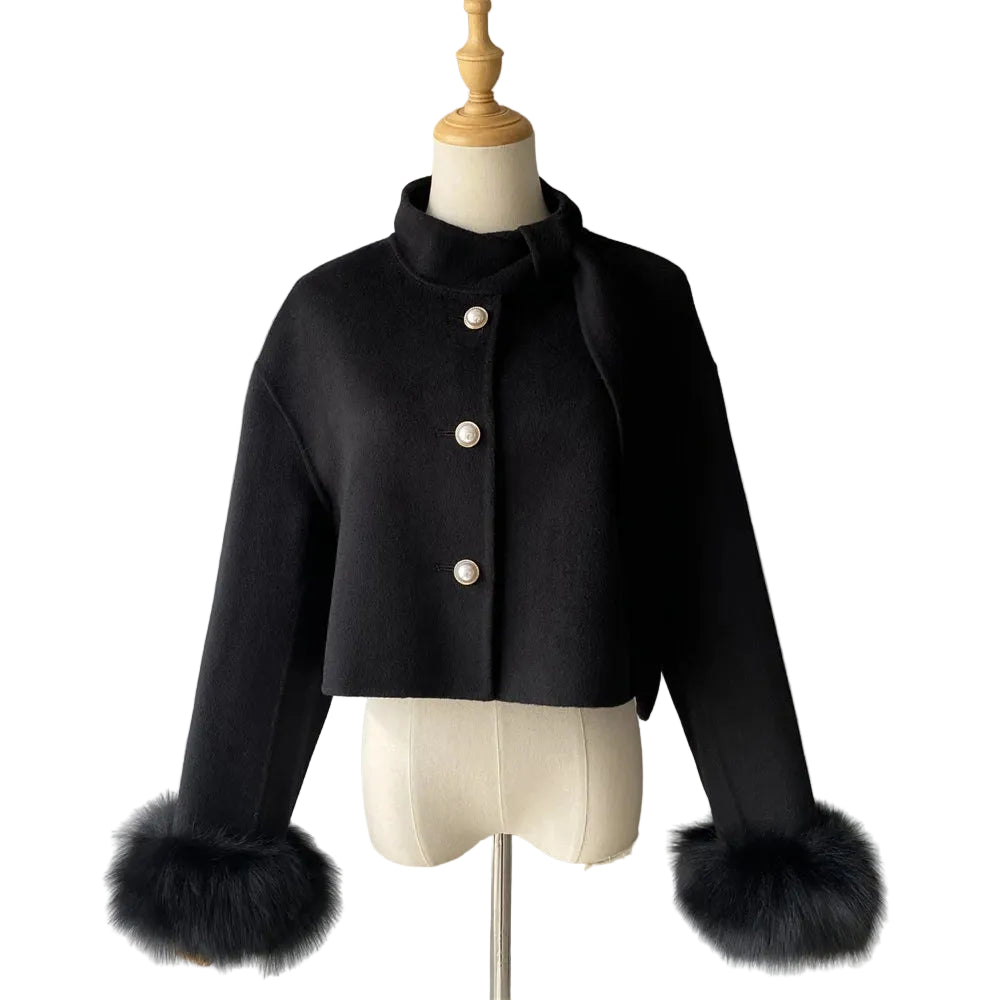 Black coat with fur cuffs on a mannequin against a plain background