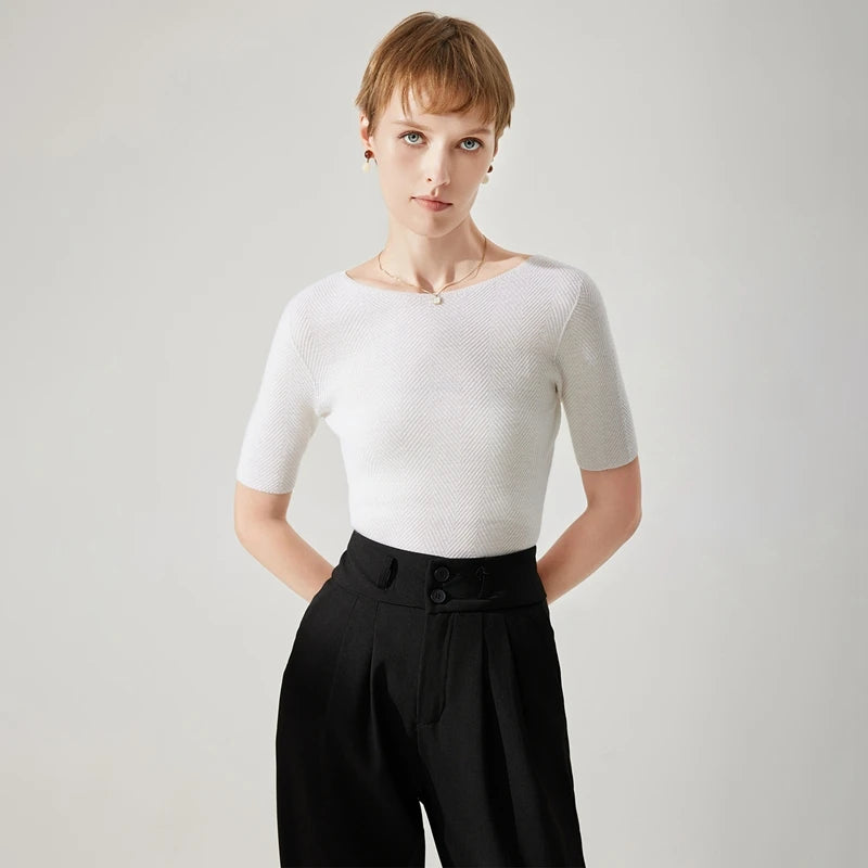 Woman wearing a white textured top and black pants on a light gray background