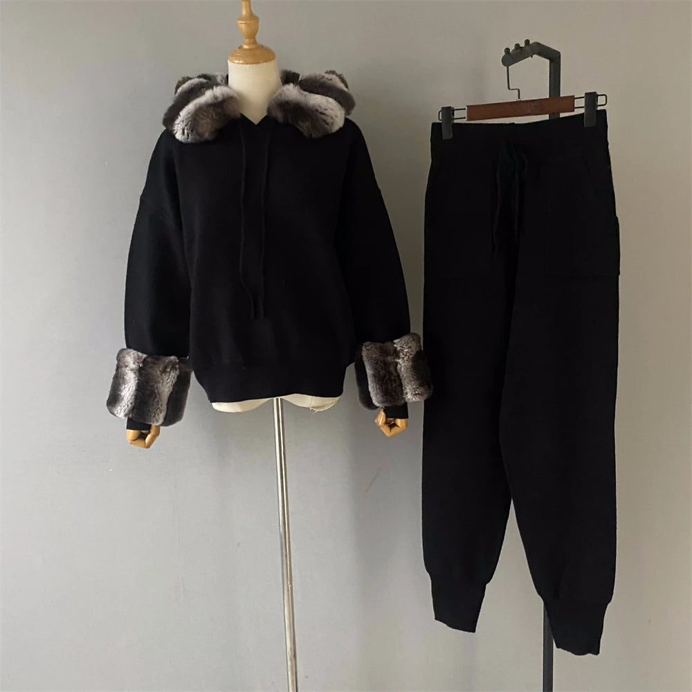 Black outfit with fur trim on a mannequin and hanger against a plain background