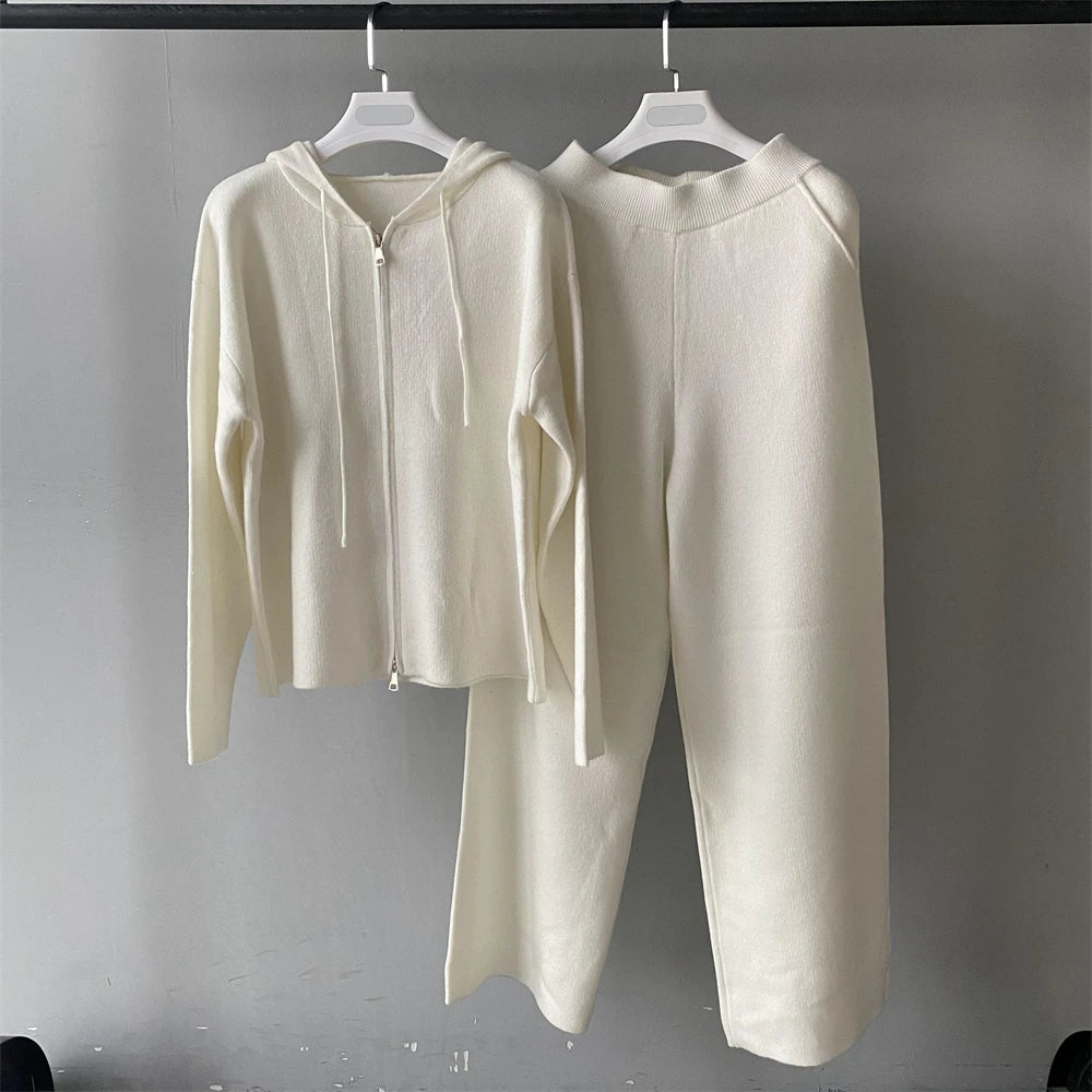 White hoodie and pants set on hangers against a gray background